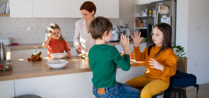 Mother of three little children preparing breakfast in kitchen at home