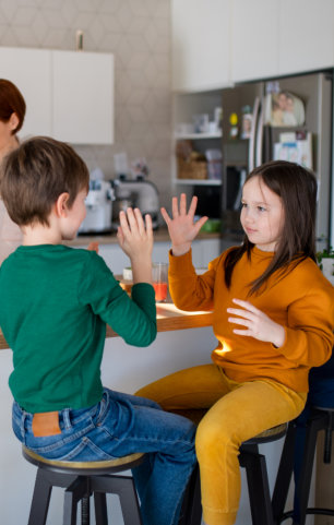Mother of three little children preparing breakfast in kitchen at home