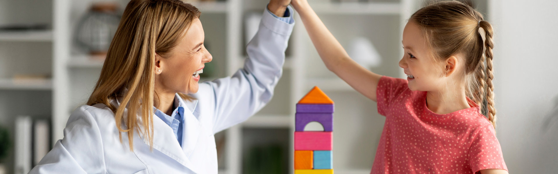 kid and woman smiling at each other and holding each other hands