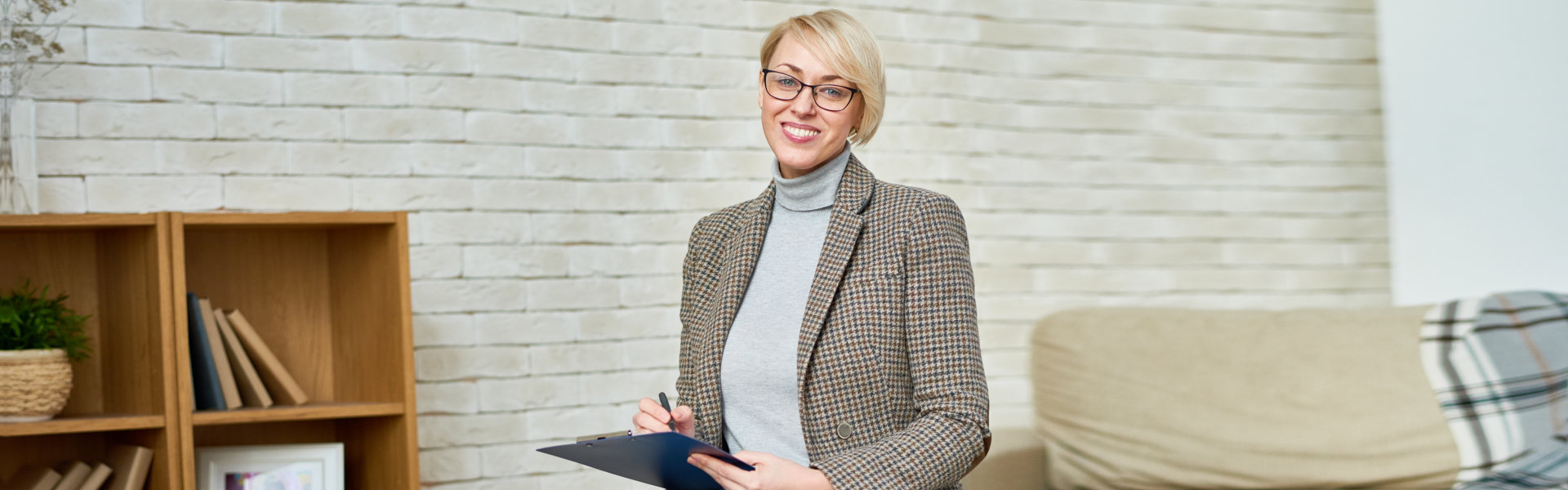 Adult woman in denim and jacket sitting in cabinet of assisted living facility smiling at camera.
