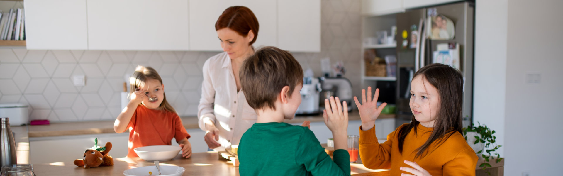 Mother of three little children preparing breakfast in kitchen at home